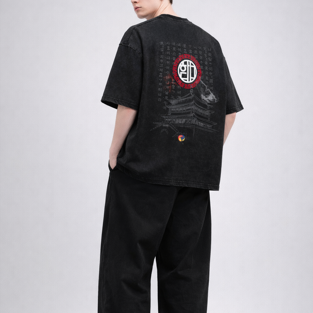 Person wearing a black t-shirt with a red and yellow symbol on the back, standing against a white background.